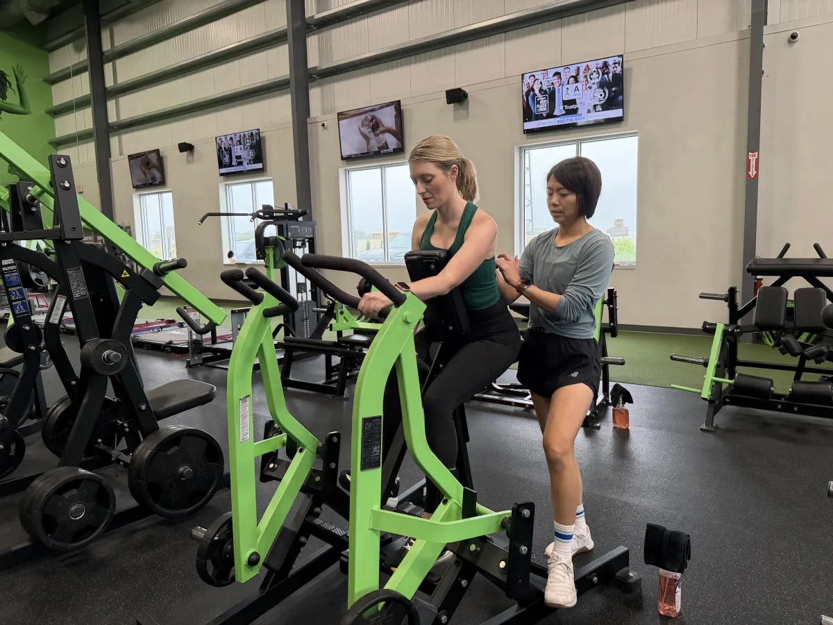 Bonnie coaching a client on a strength machine