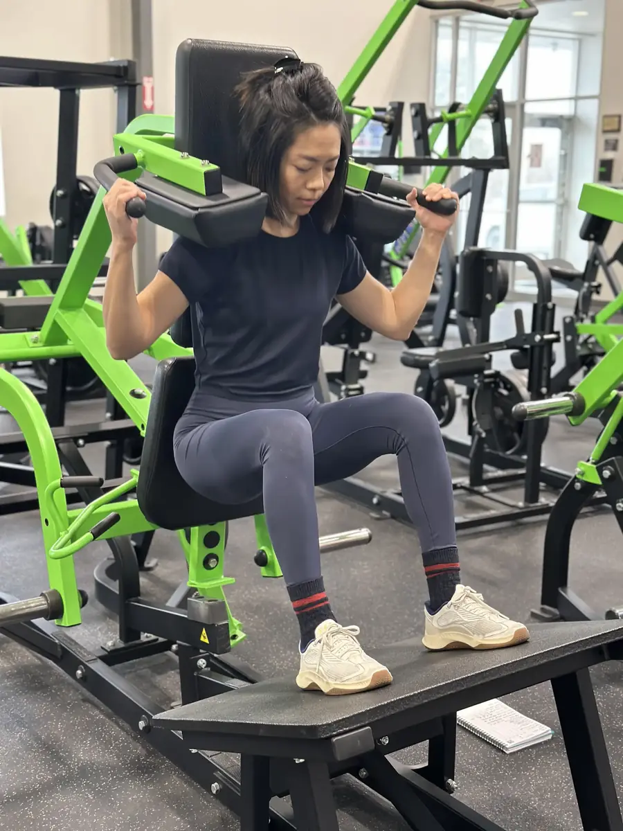 Bonnie Lin training on a plate-loaded shoulder press machine