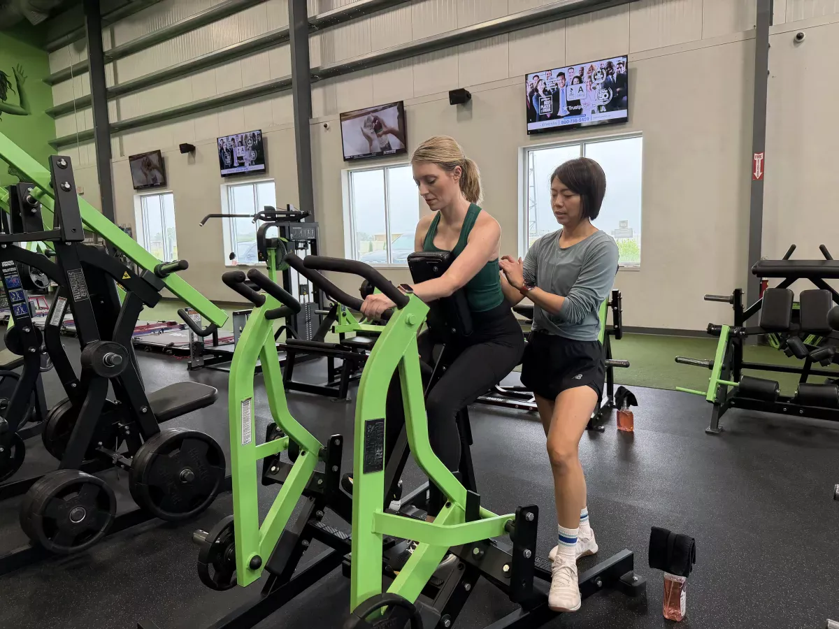 Bonnie coaching a client on a strength machine
