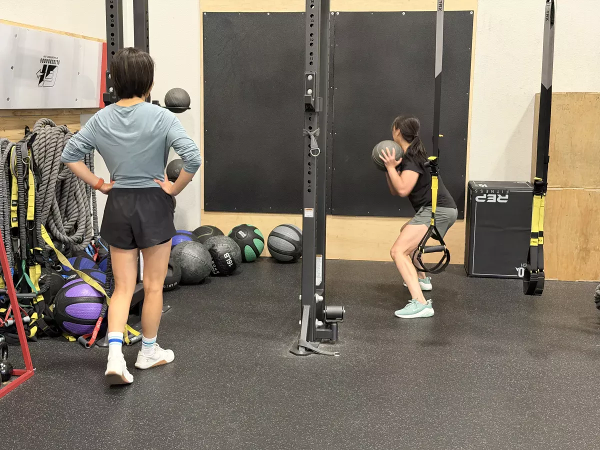 Bonnie coaching a client through a medicine-ball squat